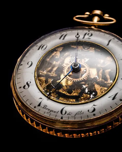 An antique gold pocket watch with its movement showing
